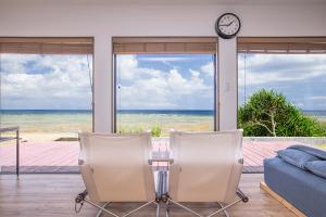 a living room with a table and two chairs and a clock at ゴールデンマイルヴィラ in Amami