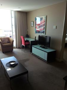 APARTMENT@96 في أديلايد: غرفة معيشة مع تلفزيون وأريكة وطاولة