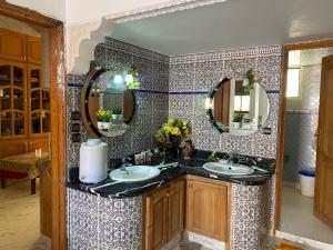 a bathroom with two sinks and two mirrors at Appartement Villa Rayhana in Khenifra