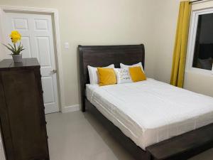 a bedroom with a bed with yellow pillows at Natalia’s Sweet Oasis in Lucea