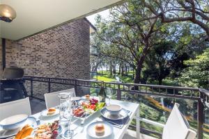 uma mesa branca com comida em cima de uma varanda em Bay Parklands, 29 2 Gowrie Avenue - views, air conditioning, Wi-Fi, Pool, tennis court and spa em Nelson Bay