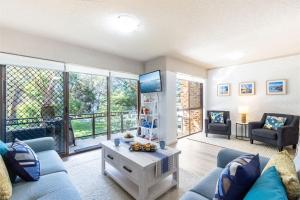 uma sala de estar com um sofá azul e uma televisão em Bay Parklands, 29 2 Gowrie Avenue - views, air conditioning, Wi-Fi, Pool, tennis court and spa em Nelson Bay