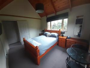 1 dormitorio con cama, mesa y ventana en Georges BnB Nature and Lifestyle Retreat en New Plymouth