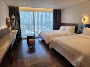 um quarto de hotel com duas camas e uma mesa em JN PARK Hotel em Incheon