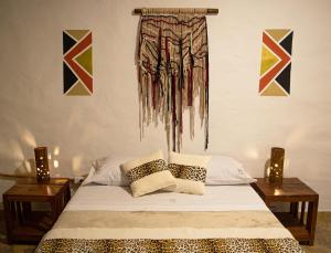 a bedroom with a bed with two tables and paintings on the wall at Refugio del Jaguar in Medellín