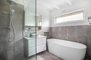 a bathroom with a tub and a sink and a shower at At Agnes Ave: coastal views in Blairgowrie +13 photos