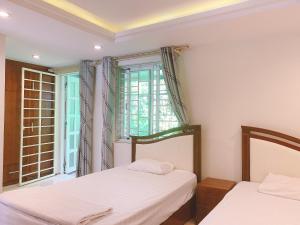 two beds in a room with a window at RosePark Tuan Chau in Ha Long