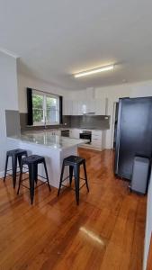 eine Küche mit einer Theke und 4 Hockern in einem Zimmer in der Unterkunft 3 bedroom Art Deco home with modern features in Burnie
