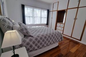 a bedroom with a bed and a lamp and a window at 3 bedroom Art Deco home with modern features in Burnie