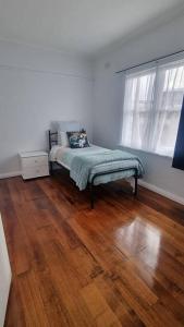 a bedroom with a bed and a wooden floor at 3 bedroom Art Deco home with modern features in Burnie