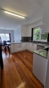 a large kitchen with white cabinets and a wooden floor at 3 bedroom Art Deco home with modern features in Burnie