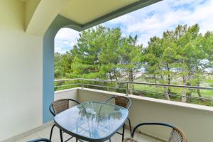 a balcony with a glass table and chairs and trees at Apartments with parking space Vrsi, Zadar - 15944 in Vrsi