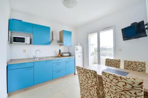a kitchen with blue cabinets and a table with chairs at Apartments with parking space Vrsi, Zadar - 15944 in Vrsi