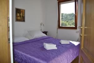 sypialnia z fioletowym łóżkiem i oknem w obiekcie Holiday house with a swimming pool Stomorska, Solta - 15950 w mieście Grohote