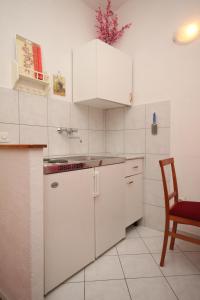 a kitchen with white cabinets and a table and a chair at Studio Brela 2713d in Brela