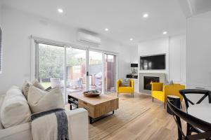 a living room with a white couch and yellow chairs at Capella Villa No. 2 - luxury with outdoor kitchen in Blairgowrie