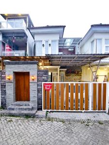 een huis met een houten hek ervoor bij Rumah Kartika Batu in Batu