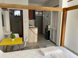 Un dormitorio con una mesa amarilla y una cocina en Urban studios, en Kilifi