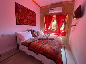 een slaapkamer met een bed en een raam met rode gordijnen bij Hotel Murad Haveli Jaisalmer in Jaisalmer