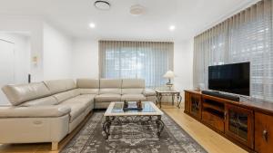 un salon avec un canapé et une télévision à écran plat dans l'établissement Coastal House, à Gold Coast