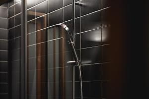 um chuveiro na casa de banho com azulejos pretos em THE HOTELS HAKATA Harushige SHINKAN em Fukuoka