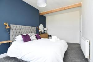 a bedroom with a large white bed with purple pillows at The John Muir - Beautiful 1 bed apartment in Helensburgh in Helensburgh