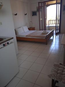 a bedroom with a bed and a kitchen with a window at Malia budget in Pírgos