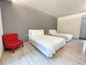 una camera da letto con due letti e una sedia rossa di 墾丁外婆家 a Città Vecchia di Hengchun