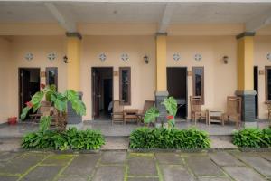 a building with chairs and plants in front of it at Pelangi Homestay Bedugul RedPartner in Bedugul