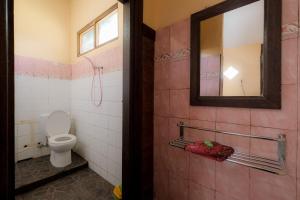 a bathroom with a toilet and a mirror at Pelangi Homestay Bedugul RedPartner in Bedugul