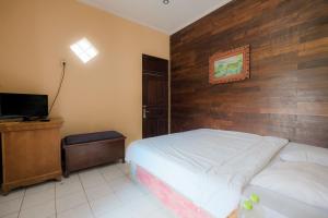 a bedroom with a bed with a wooden wall at Pelangi Homestay Bedugul RedPartner in Bedugul +15 photos