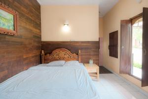 1 dormitorio con 1 cama con pared de madera en Pelangi Homestay Bedugul RedPartner, en Bedugul