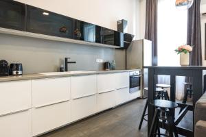 a kitchen with white cabinets and a counter with stools at Luxury Nova Home next to the New York Café in Budapest