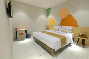 a bedroom with a bed and a tv on a wall at Genio Inn - MANTOS in Manado