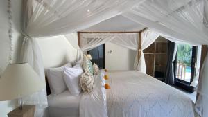 a bedroom with a white bed with a canopy at The Palms Canggu in Canggu