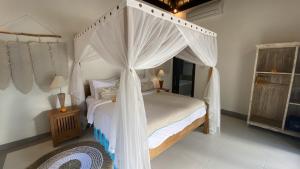 a bedroom with a canopy bed with white curtains at The Palms Canggu in Canggu