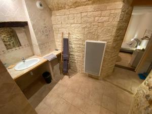 a bathroom with a sink and a stone wall at La Fontaine de Vinsobres in Vinsobres