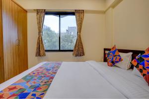 a bedroom with a large bed and a window at FabHotel Crystal Homes in Pune