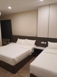 2 bedden in een hotelkamer met witte lakens bij T SQUARE HOTEL (IPOH) in Ipoh