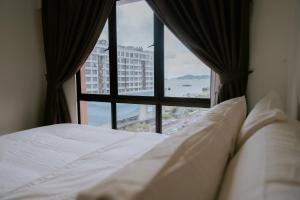 łóżko w pokoju hotelowym z dużym oknem w obiekcie Petronella Apartment C1 Marina Court w mieście Kota Kinabalu