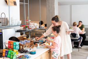 een vrouw en een klein meisje die eten klaarmaken in een keuken bij Rewindhotel in Oostduinkerke