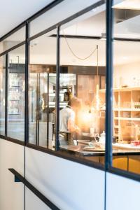 - un chef préparant des plats dans une cuisine à travers une fenêtre dans l'établissement Rewindhotel, à Oostduinkerke