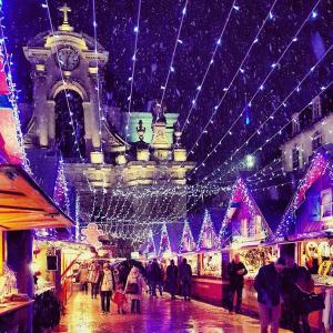 un grupo de personas caminando por un mercado con luces de Navidad en Au Bon Vieux Port Maison de vacances Alsacienne à 10mn de Ribeauvillé, Riquewihr et Kaysersberg en Sélestat