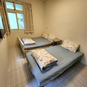 três camas num quarto com uma janela em 春季優惠 續住半價 太麻里 左奶奶的家 em Taimali
