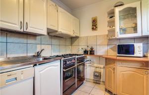 La cuisine est équipée de placards blancs et d'un four avec plaques de cuisson. dans l'établissement 8 Bedroom Beautiful Home In Miastko, à Starzno