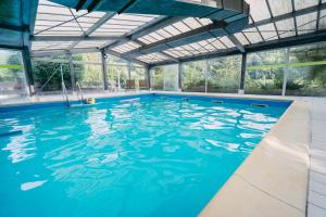 an indoor swimming pool with blue water at Village Vacances Le Mongade (by Popinns) in Plainfaing