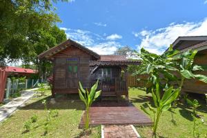 a small house with a wooden deck in the yard at Collection O 90622 Sehijau Cenang in Pantai Cenang