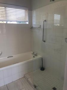 a white bathroom with a tub and a shower at Boggoms' View in Boggomsbaai