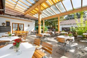 un patio al aire libre con mesas, sillas y toldo en Hotel Neuwirt en Hallbergmoos