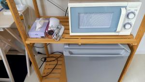 un microondas sentado en la parte superior de un mostrador junto a una nevera en Guest house Shijo K12 D401 en Kyoto